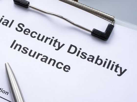 A disability benefits application on a clipboard, with a pen resting on it
